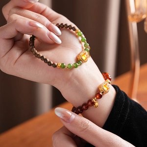 Detailed close-up of orange garnet and jasper gourd bracelets on a female wrist