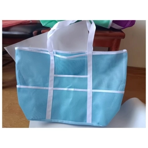 Vue détaillée d'un sac de plage en filet bleu clair avec sangles blanches et poches de rangement