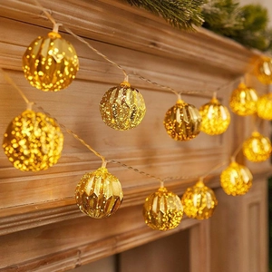 Golden LED crackle glass ball string lights on a wooden mantel with pine branches decoration