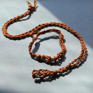 Detailed close-up of brown hand-woven mesh necklace cord with decorative wooden beads