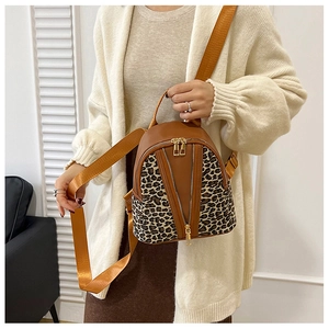 Detail of mini leopard print backpack with brown leather trim and dual gold V-shaped zippers
