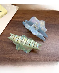 Iridescent iridescent blue and green cloud hair claws with wave edges on a wooden table
