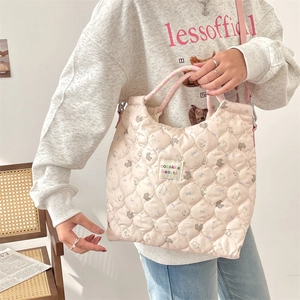 Vue lifestyle d'un sac à main matelassé rose avec motif ours et bandoulière porté par mannequin