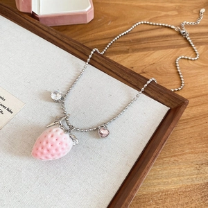 Detail view of silver bead chain necklace featuring a pink strawberry and heart charms