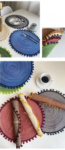Detailed close-up of colorful round woven placemats featuring decorative pom-pom edges
