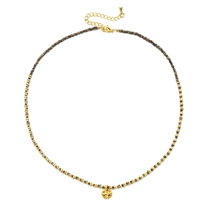 Detail of bohemian gold beaded necklace with a hand-hammered round pendant and 18K finish