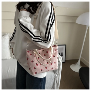 Detailed texture of pink strawberry print corduroy bag with dual handle and shoulder strap