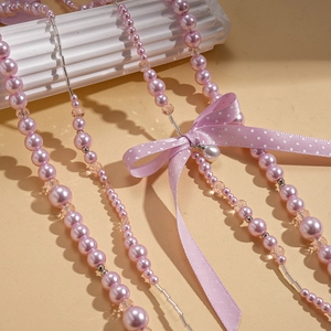 Détail du collier de perles en verre rose avec nœud strass et pompon goutte d'eau