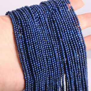Macro shot of 2mm dark blue natural stone lapis lazuli beads held by hand for DIY jewelry