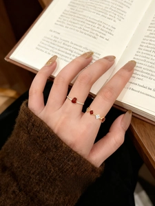 Close-up of 18k gold plated gourd and heart rings worn with a brown sweater