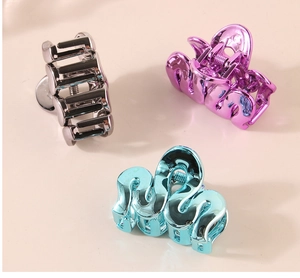 Detailed view of polished wave-shaped alloy hair claws in silver, purple and blue finishes