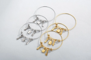 Detail view of gold and silver stainless steel lock and key charms on minimalist bangles