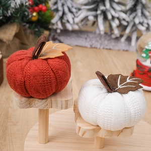 Knitted decorative pumpkins in red and white colors on a wooden stand for harvest decor