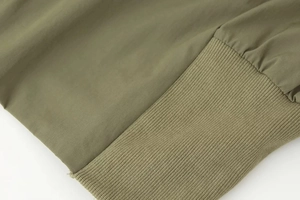 Détail du tissu tissé vert armée avec poignets côtelés élastiques sur veste à col montant