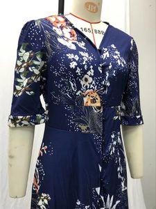 Détail d'une robe bleu marine à col en V avec imprimé floral et boutons noirs