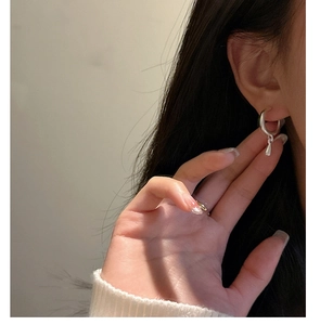 Close-up of a minimalist S925 sterling silver waterdrop earring worn on an ear