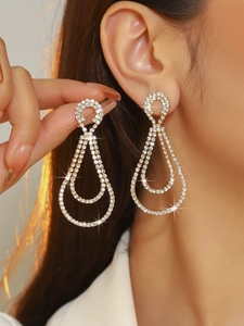 Macro detail of luxury gold double teardrop rhinestone earrings on a model