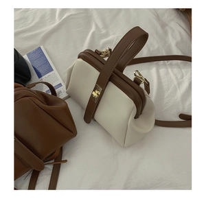 Detail shot of vintage contrast醫生 hand bags with metal clasps on white linen bedding