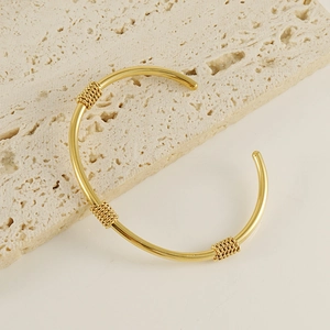 Detailed close-up of a 18K gold-plated C-shaped cuff bangle with spiral wire accents