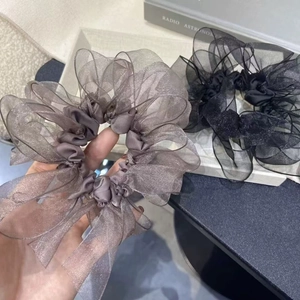 Dettaglio degli elastici scrunchie in organza grigia e nera con texture luccicante