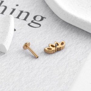 Macro view of gold-plated titanium labret stud with decorative hollowed-out leaf head