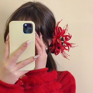 Detail of red Lycoris flower hair clip worn on model side hair with a red sweater