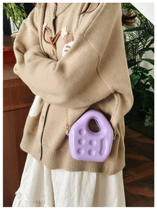 Detail of a purple PVC mini jelly bag featuring a circular handle and gold chain strap