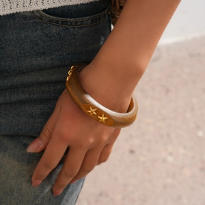 Close-up of geometric acrylic bangle with wood texture and gold star rivet studs