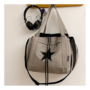Gray nylon crossbody bag featuring a black star logo and drawstring closure hanging on a hook