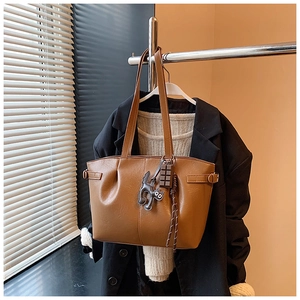 Close-up of brown tote bag with cute black cat and chocolate block charms on handle