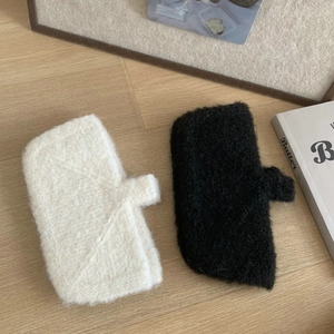 Detail view of plush black and white gloves on a cozy wooden background with books