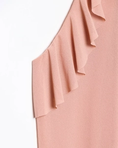 Detail shot of the ruffled neckline and fine knitted texture on pink halter top