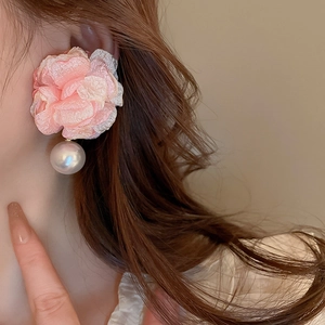 Close-up of a pink fabric flower earring with a large white pearl bead on model
