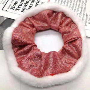 Close-up of a festive red sparkling scrunchie with white plush trim on a newspaper background