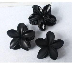 Detailed view of three black floral hair claws in matte and polished finishes