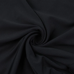 Detailed close-up of high-quality black knitted fabric with elegant drapes and soft texture