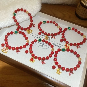 Detailed view of six red beaded bracelets with golden pony pendants on a display tray