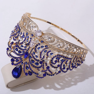 Detailed close-up of golden crown featuring blue teardrop stones and intricate water wave patterns