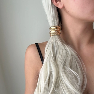 Detailed view of a sleek golden metallic hair tie securing a ponytail in a French style