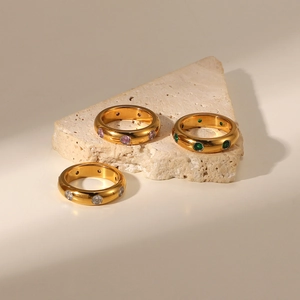 Close-up of three vintage gold rings set with green, pink, and white zircon stones