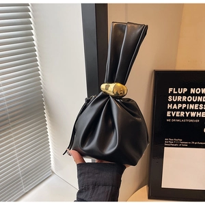 Detailed view of black leather drawstring bag with unique irregular gold metal buckle closure