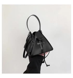Detail of gothic triangle handbag featuring metal cross and chain on black PU leather