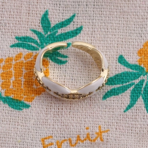 Detail of adjustable gold ring with white enamel sections and pave cubic zirconia stones