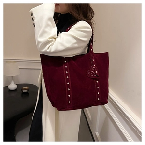 Detail of burgundy suede tote bag featuring silver rivet trim and heart-shaped pendant