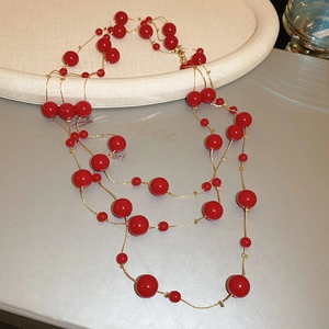 Detailed view of layered deep red beaded necklace with elegant gold chain links