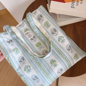 Détail d'un sac fourre-tout en coton rayé bleu avec illustration vintage et poignées