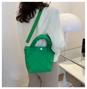 Model wearing a bright green quilted nylon crossbody bag with diamond stitch patterns