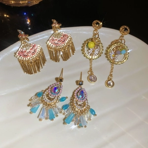 Detailed view of vintage gold-plated drop oil tassel earrings displayed on a white tray