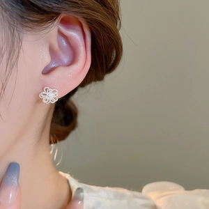 Close-up of minimalist silver hollow flower stud earring worn on model's ear