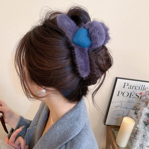 Detailed view of a plush purple hair claw with blue hearts on a woman's hair style